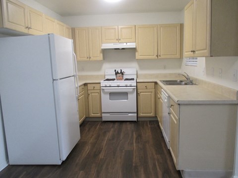 an empty kitchen with white appliances and wooden cabinets